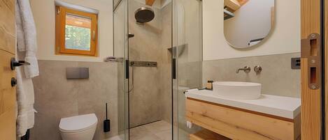 Ein modernes Badezimmer mit einer Glasdusche, einer weißen Toilette und einem Holzwaschtisch.