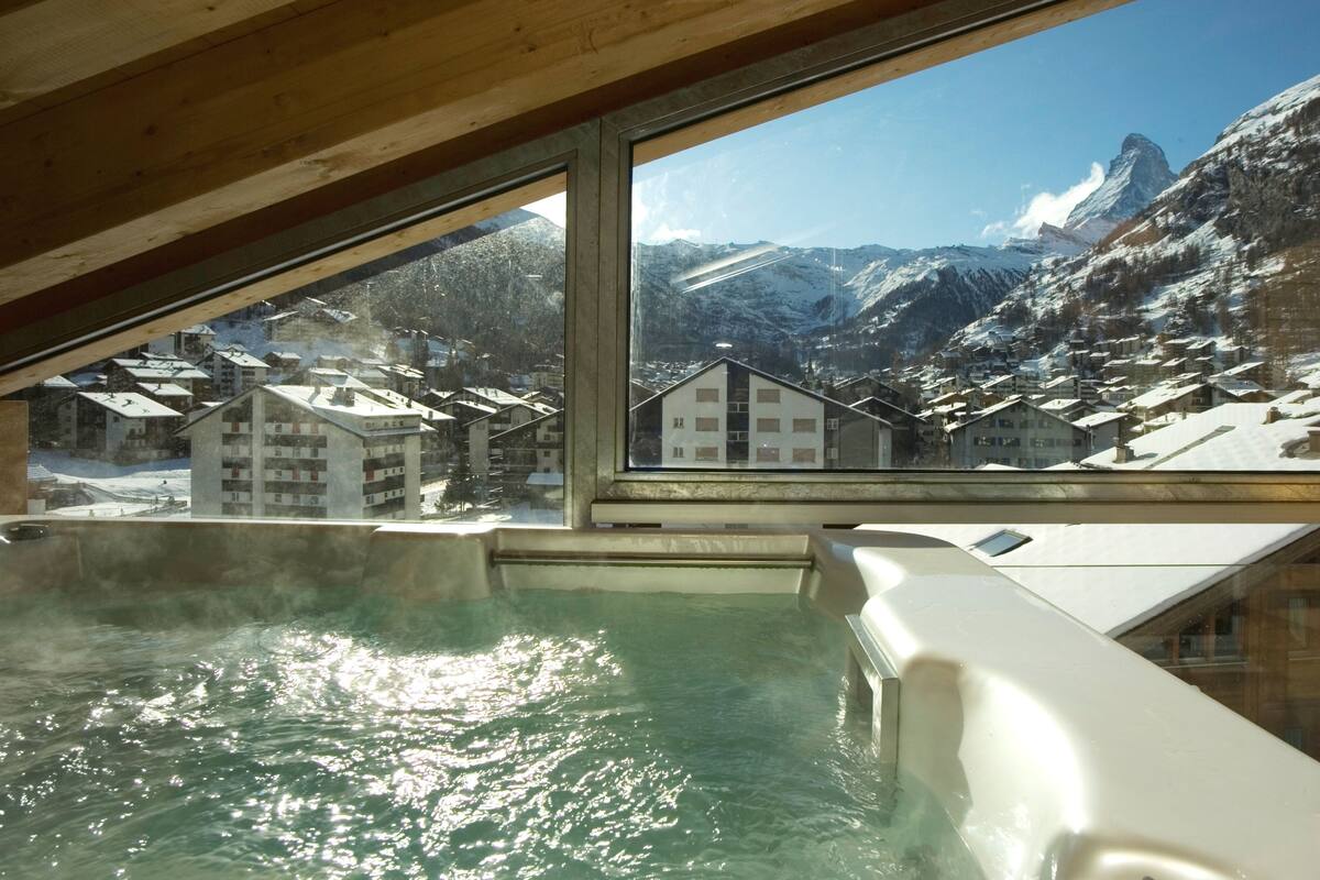 A hot spring area with a view of snow-covered buildings and mountains.