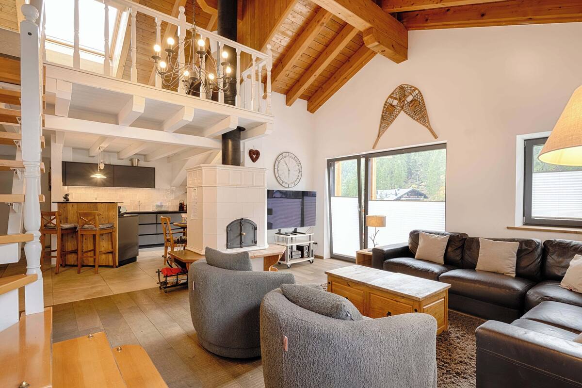 A spacious living area with a high ceiling, a fireplace, a dining area, and a kitchen.