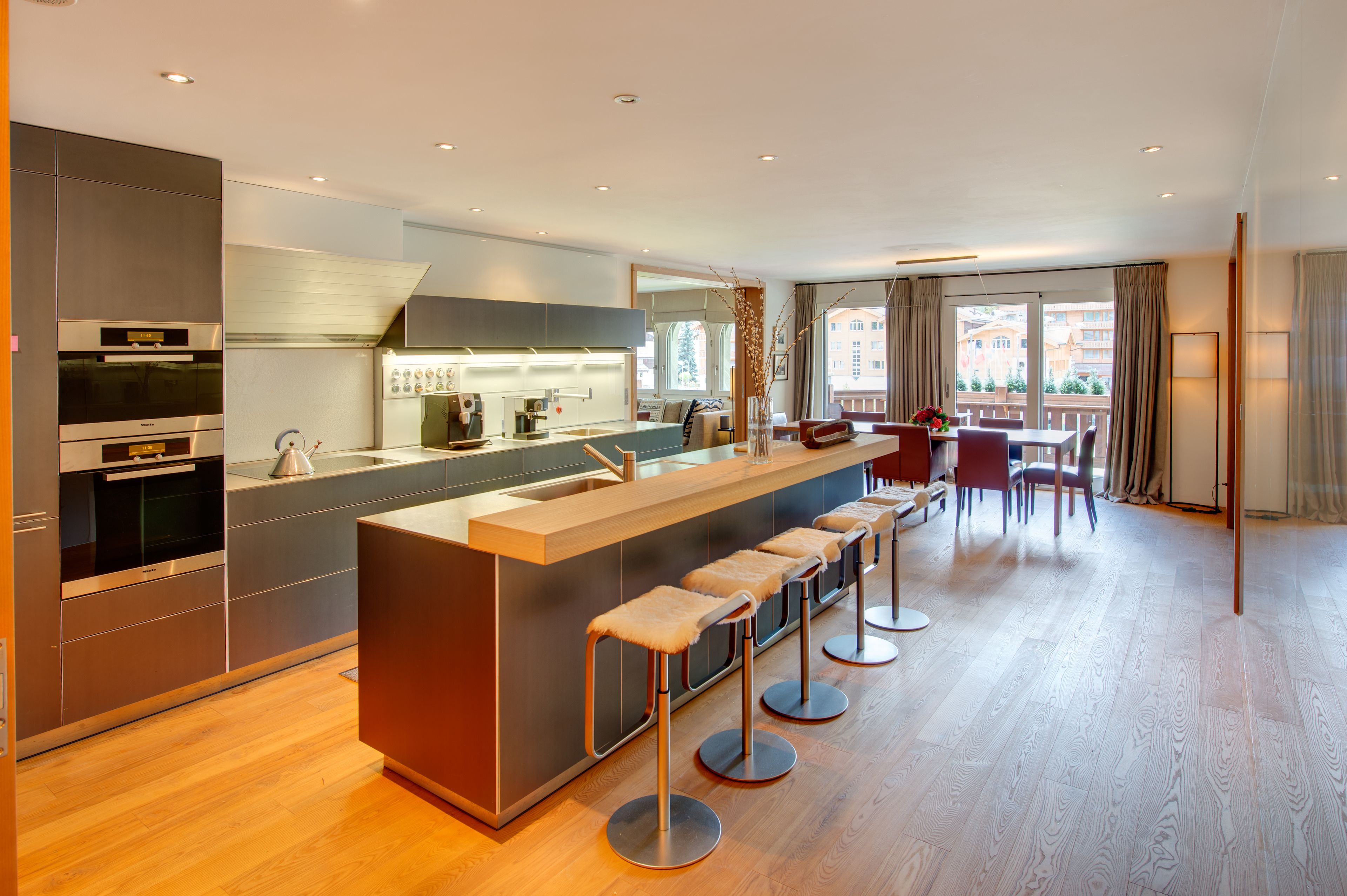 Una cocina moderna con una isla central, taburetes de bar y un comedor con vistas.