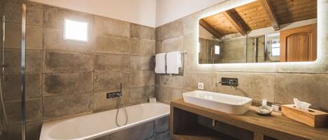 A modern bathroom with a large bathtub, a wooden vanity, and a large mirror.