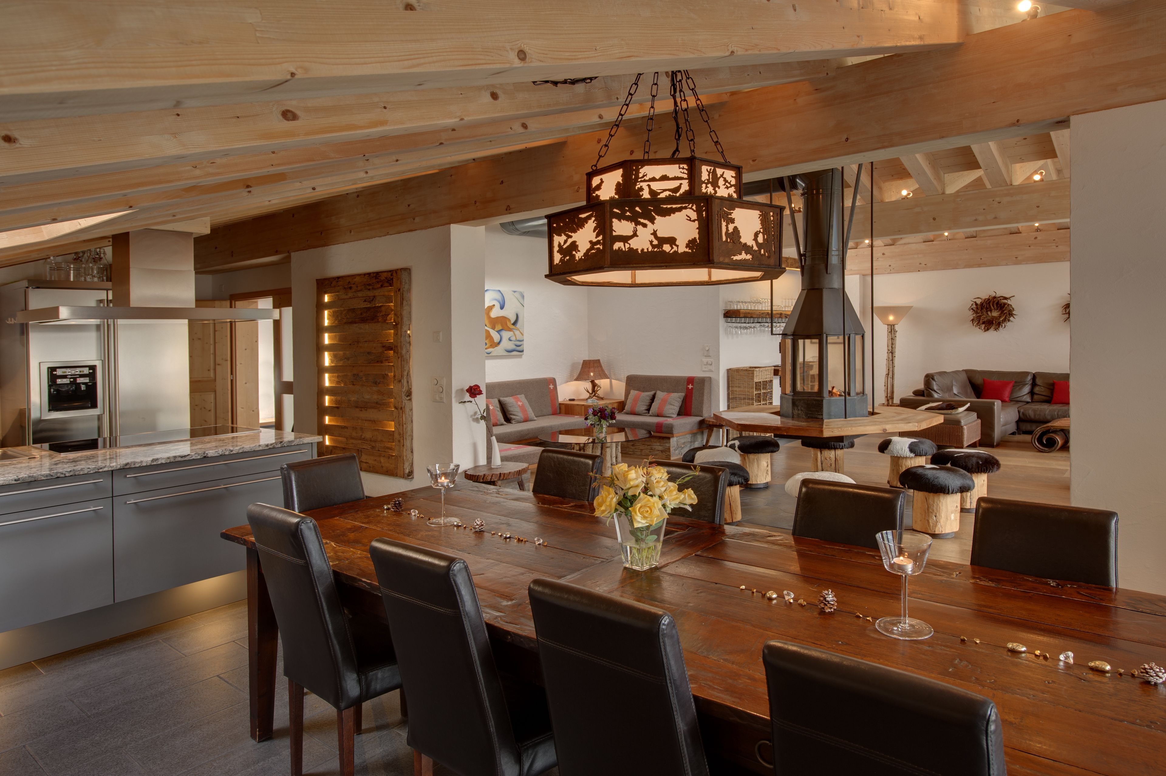A spacious dining area with a large wooden table, black chairs, and a hanging light fixture.