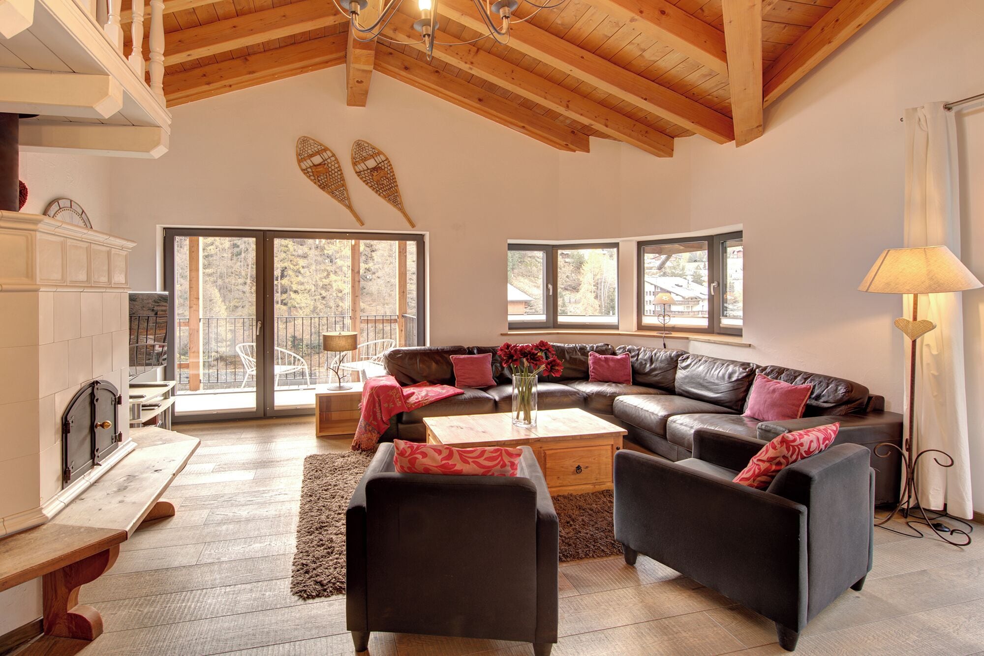 A spacious living room with a wooden ceiling, large windows, a fireplace, and a cozy seating area.