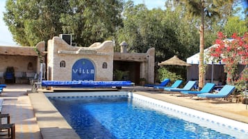 Una piscina al aire libre, camas de piscina gratis, sombrillas