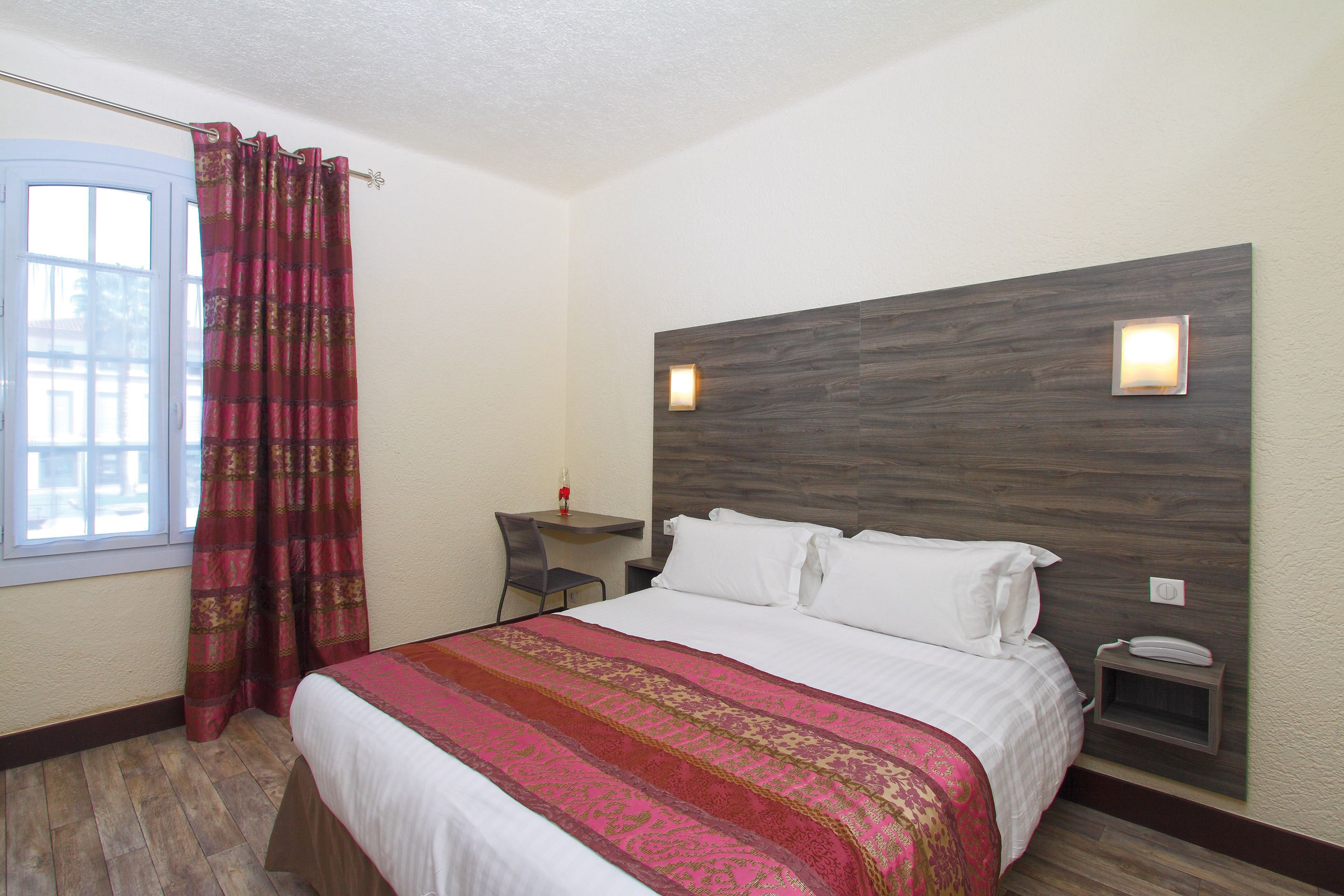 A hotel room with a large bed, a desk, and a chair.