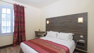 A hotel room with a large bed, a desk, and a chair.