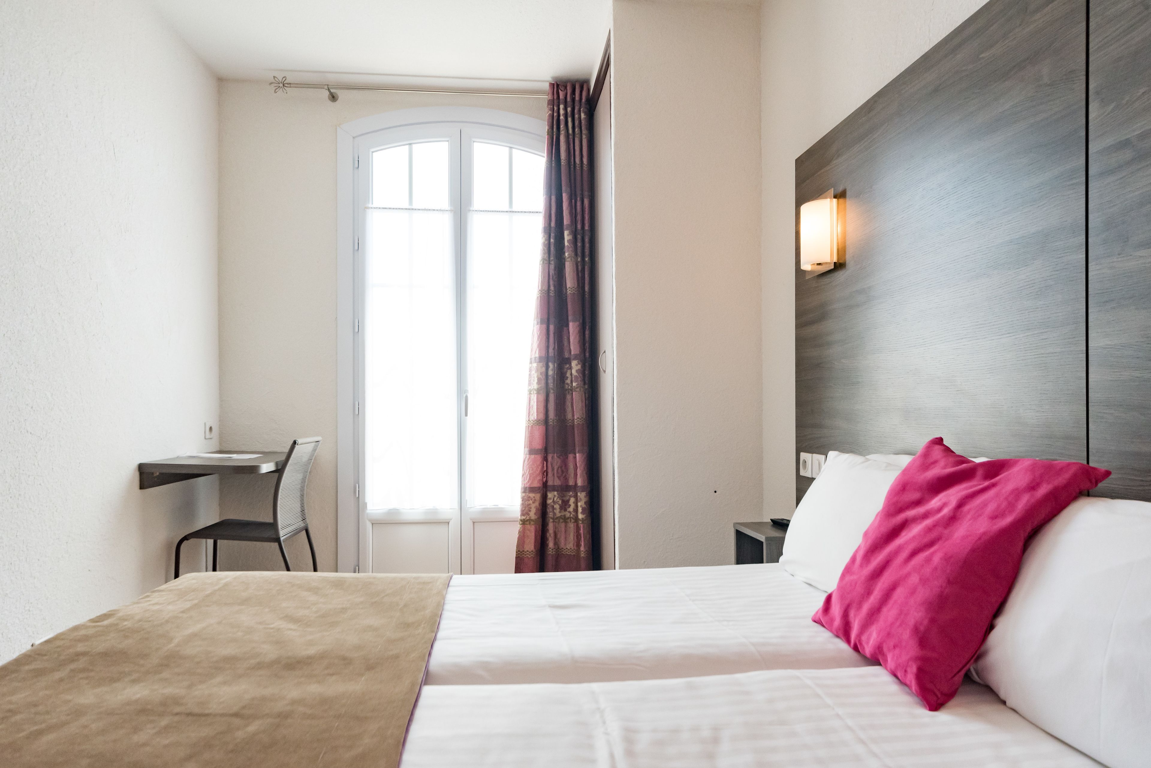 A hotel room with a bed, a desk, and a chair.