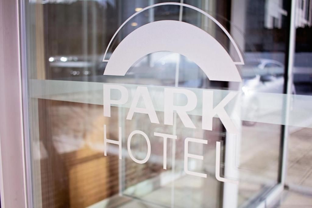 Une vitre avec l’inscription « PARK HOTEL » et un dessin stylisé représentant un toit.