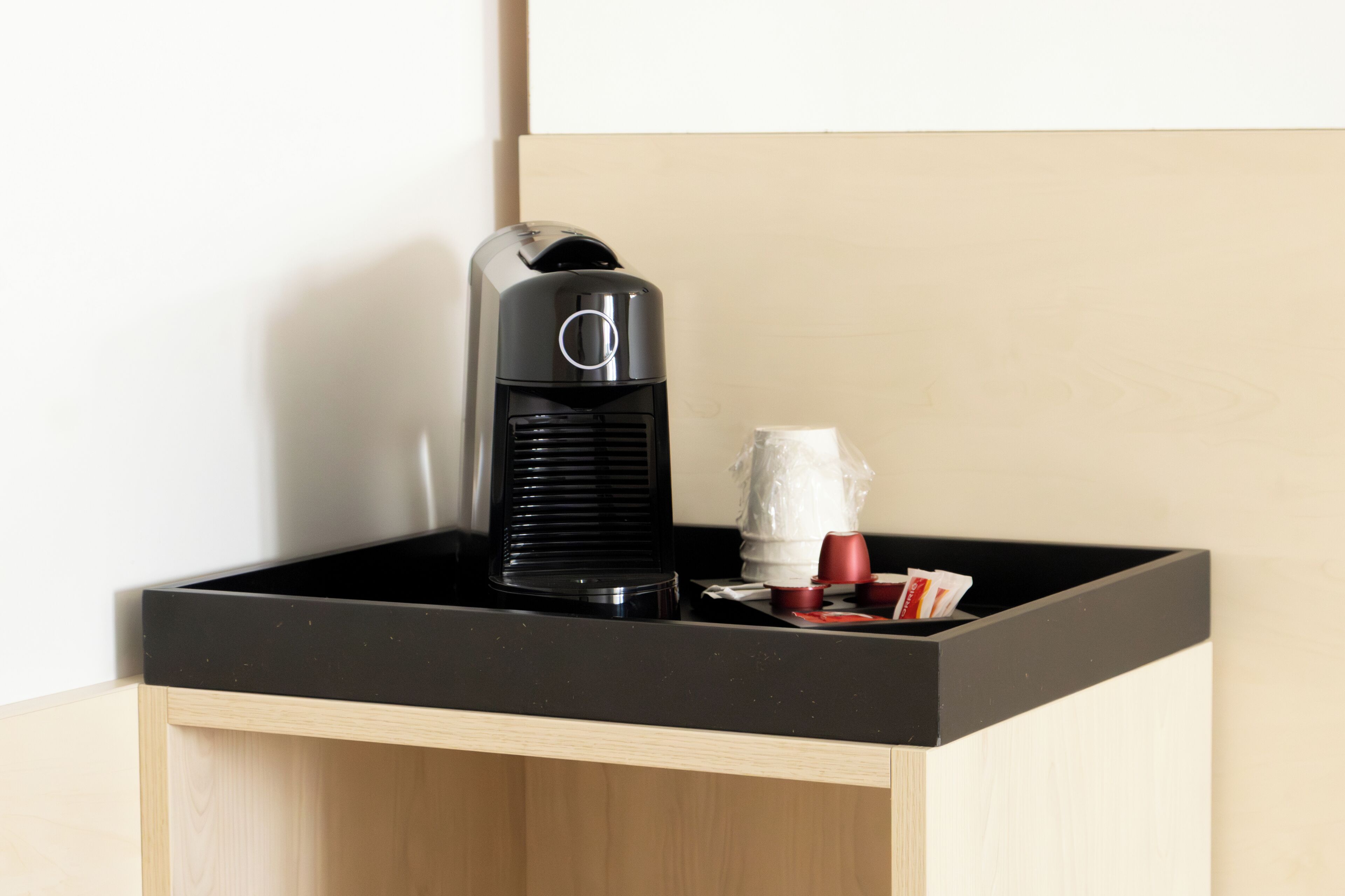 A coffee maker on a black countertop with a wooden cabinet below.