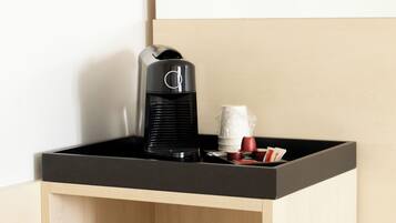 A coffee maker on a black countertop with a wooden cabinet below.