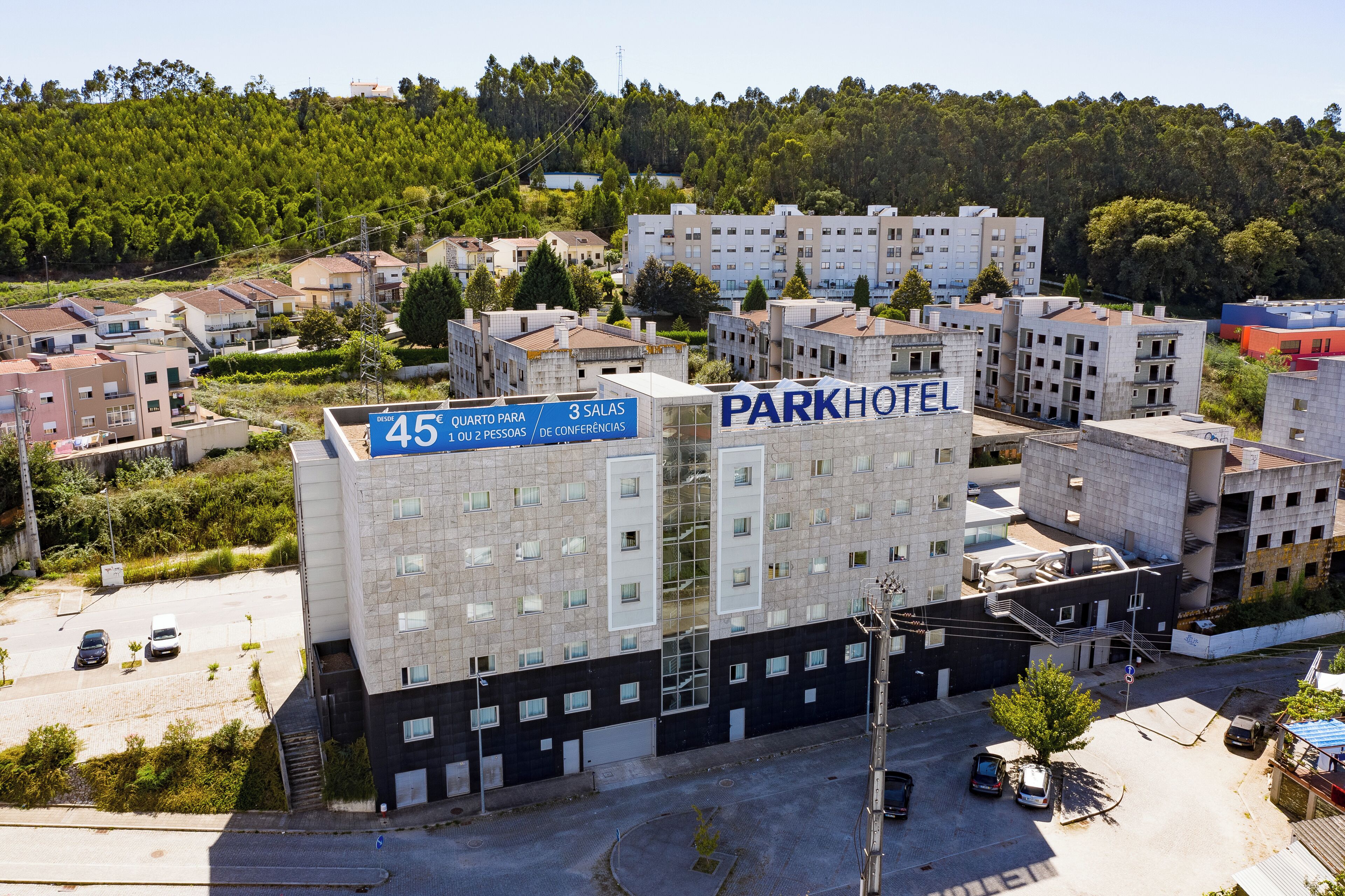 A multi-story hotel with a sign indicating a price of 45€ for 3 rooms or 2 people, and the name 'PARKHOTEL' displayed prominently.