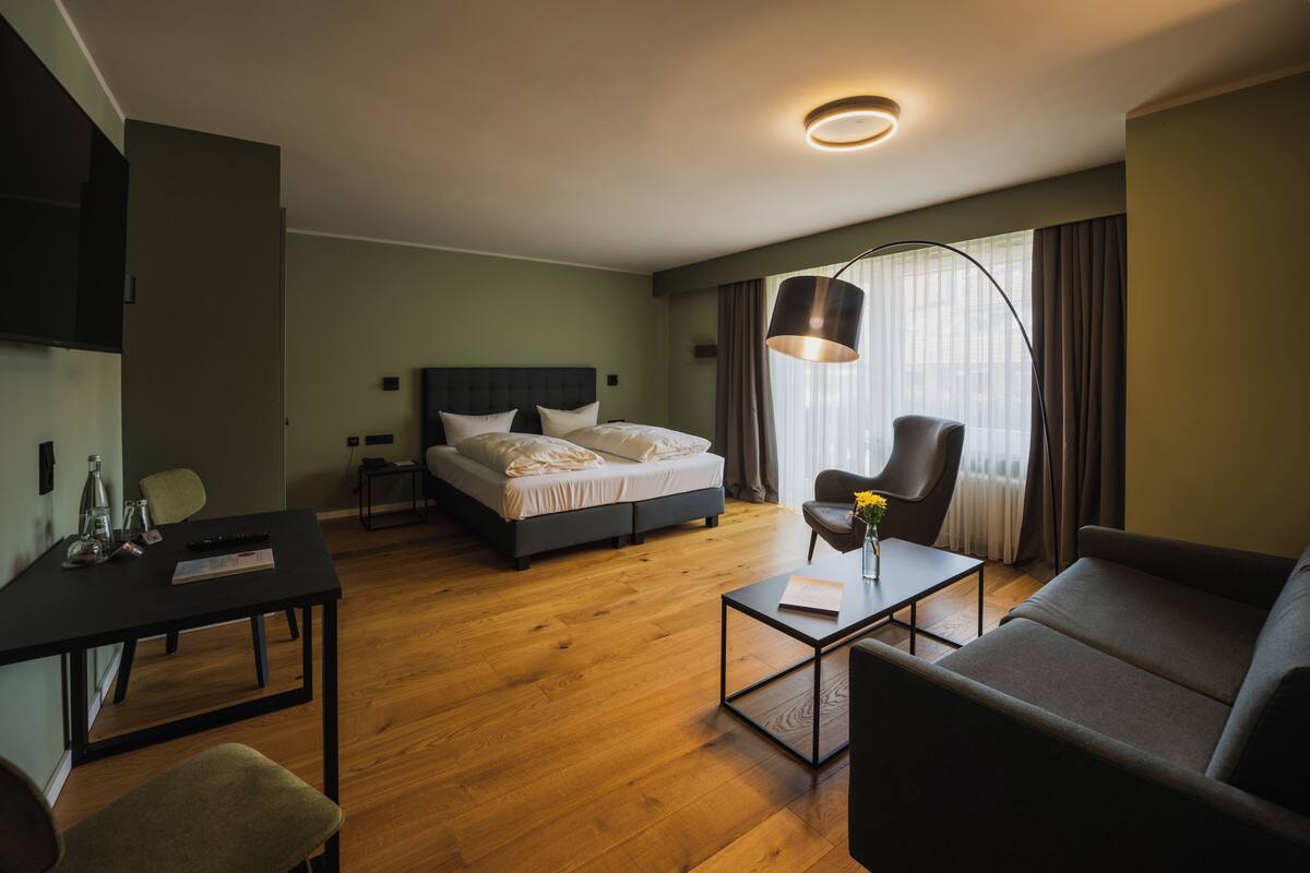 Una habitación de hotel moderna con cama, sofá, escritorio y silla.
