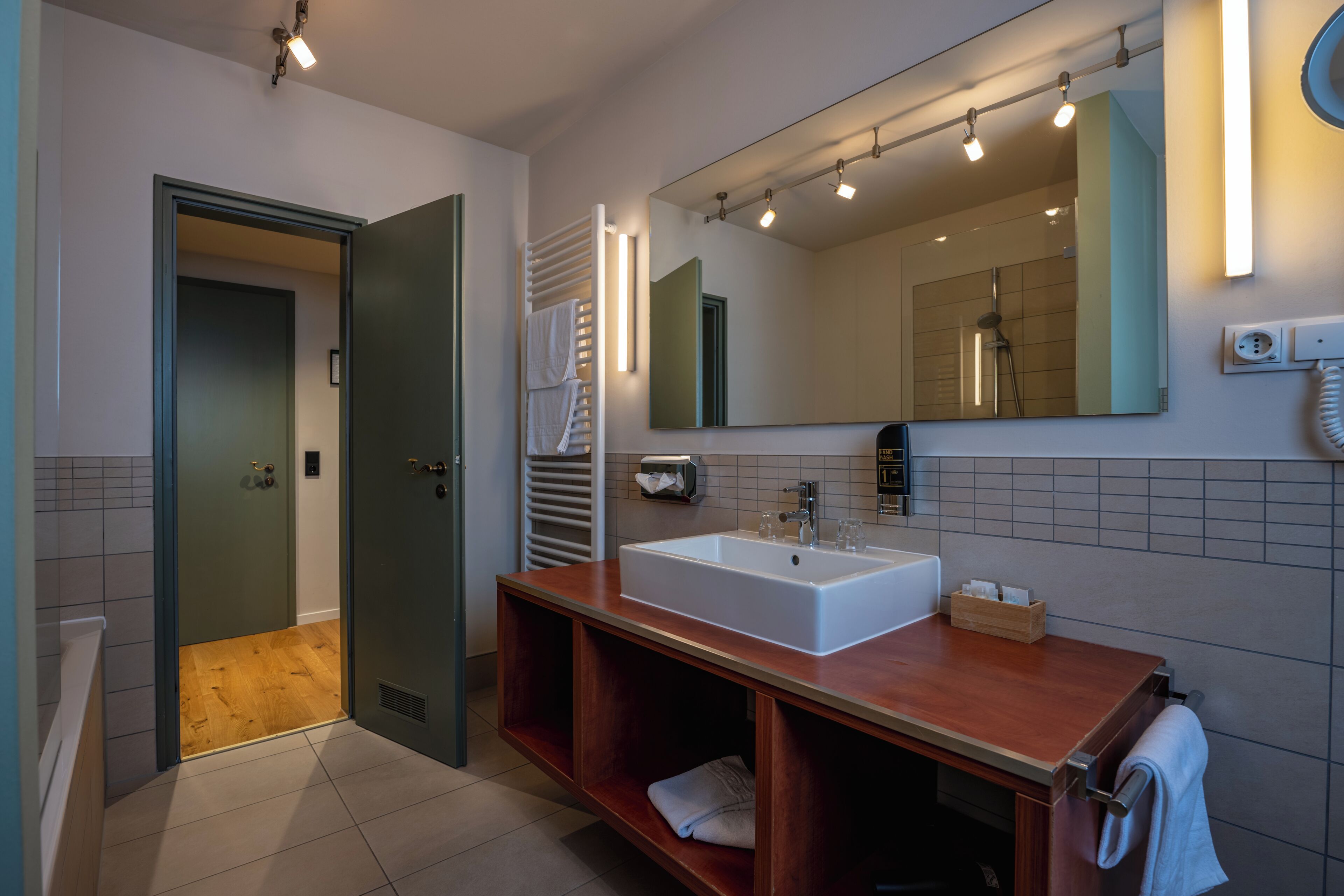 A modern bathroom with a large sink, mirror, and towel rack.