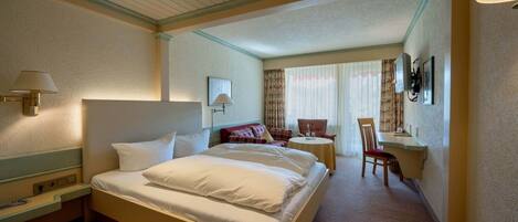 A hotel room with a large bed, bedside tables, a desk, and a chair.