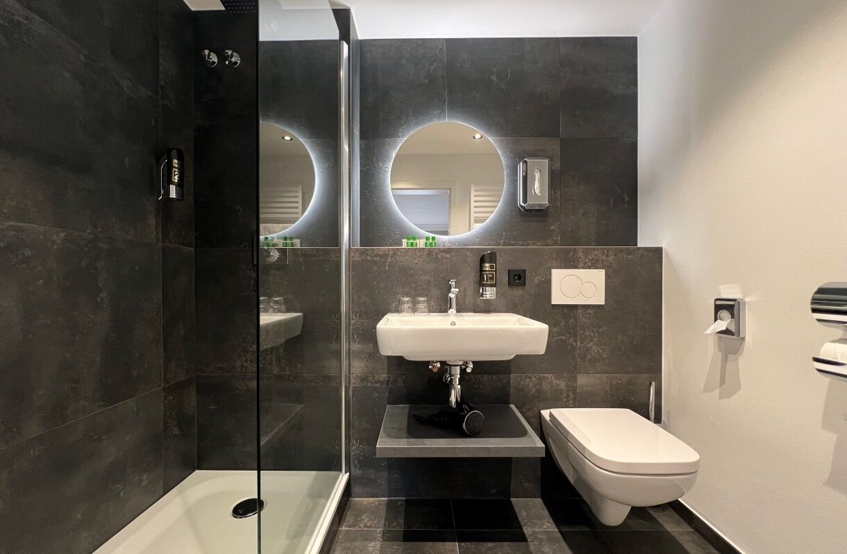 A modern bathroom with a glass-enclosed shower, a white sink, and a toilet.
