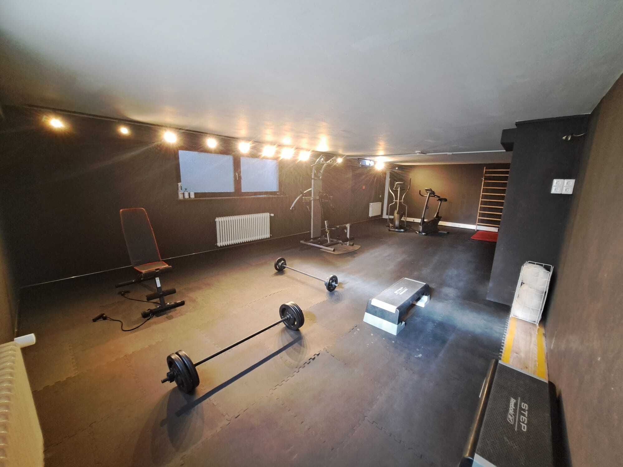 A gym with a squat rack, barbell, weight bench, and exercise machines.