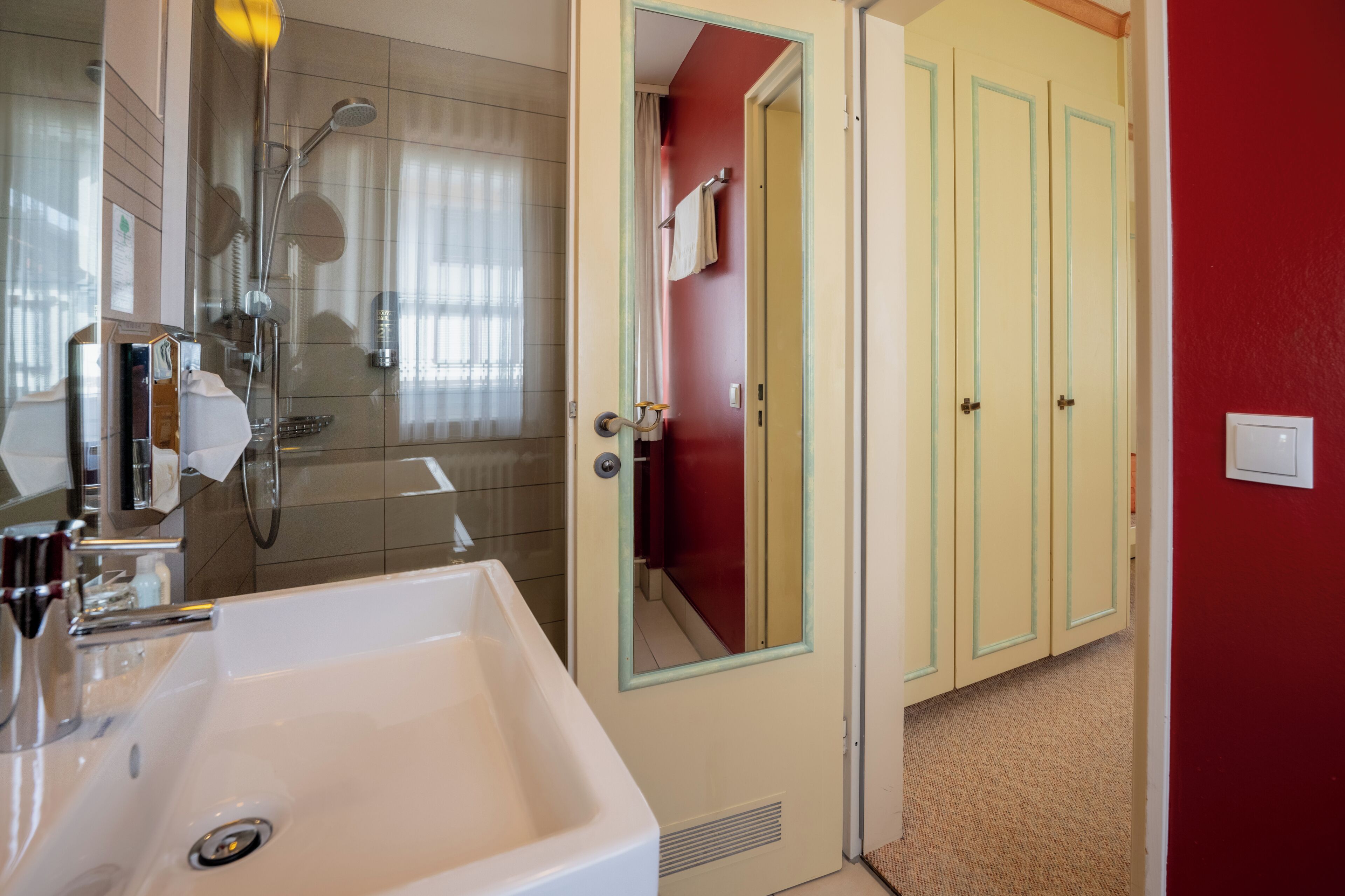 A bathroom with a shower, sink, and mirror.