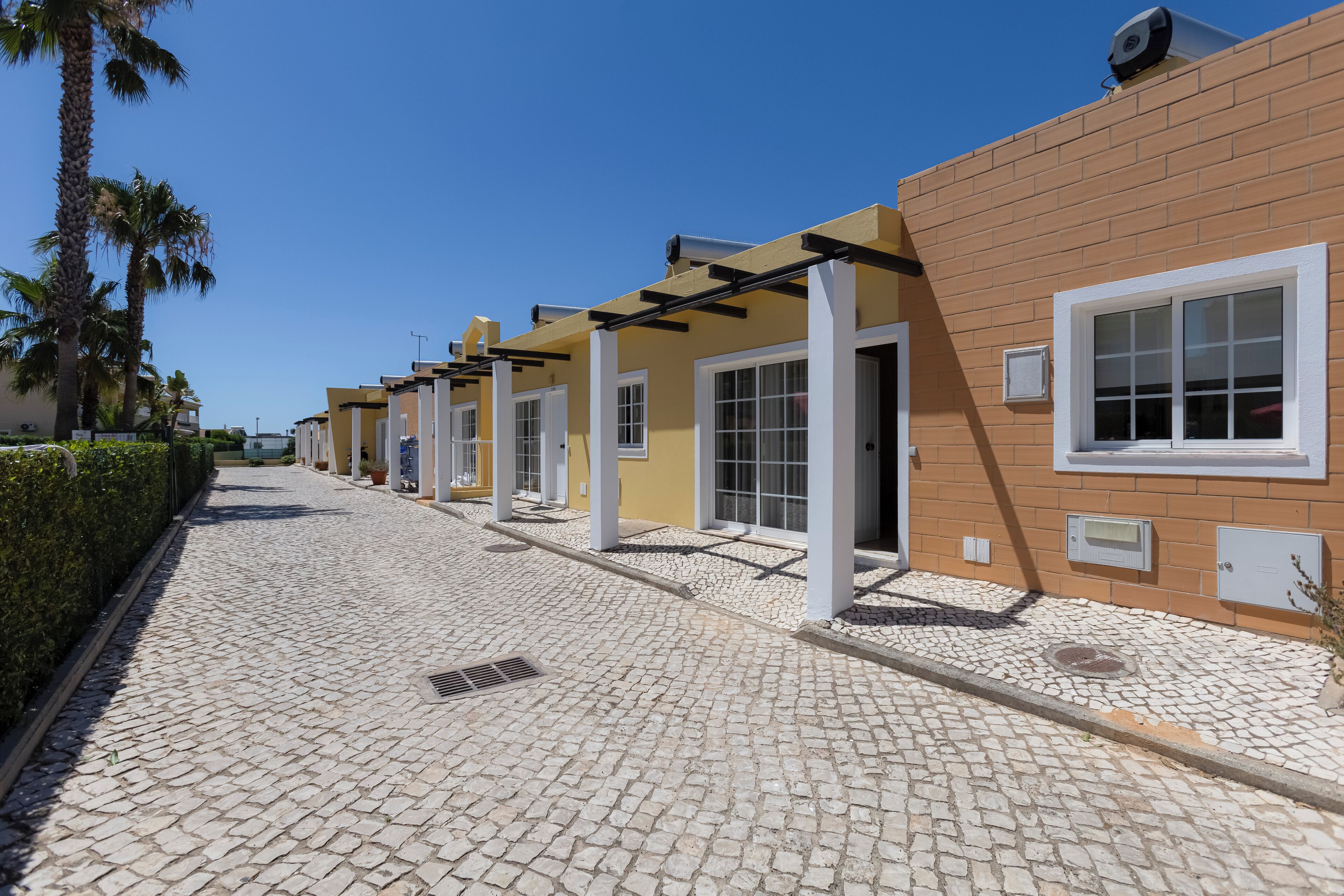 A row of buildings with white-framed windows and a paved walkway.