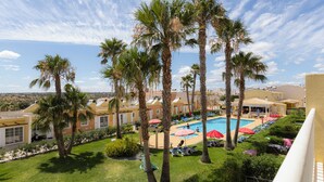 A pool area with palm trees, sun loungers, and umbrellas. - Villas Barrocal (Silves)