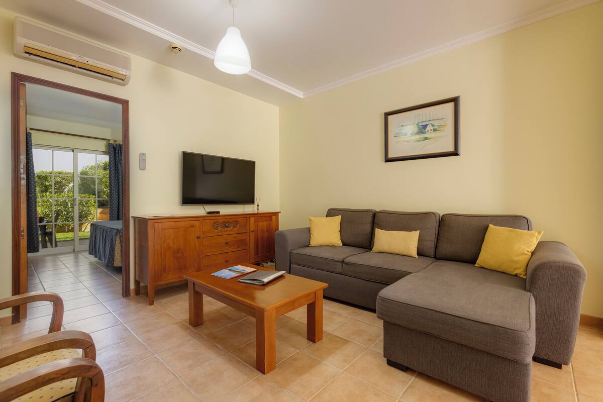 A living room with a sofa, a coffee table, a TV, and a painting on the wall.