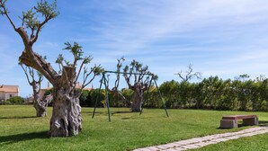 A park with a swing set, a bench, and a tree. - Villas Barrocal (Silves)