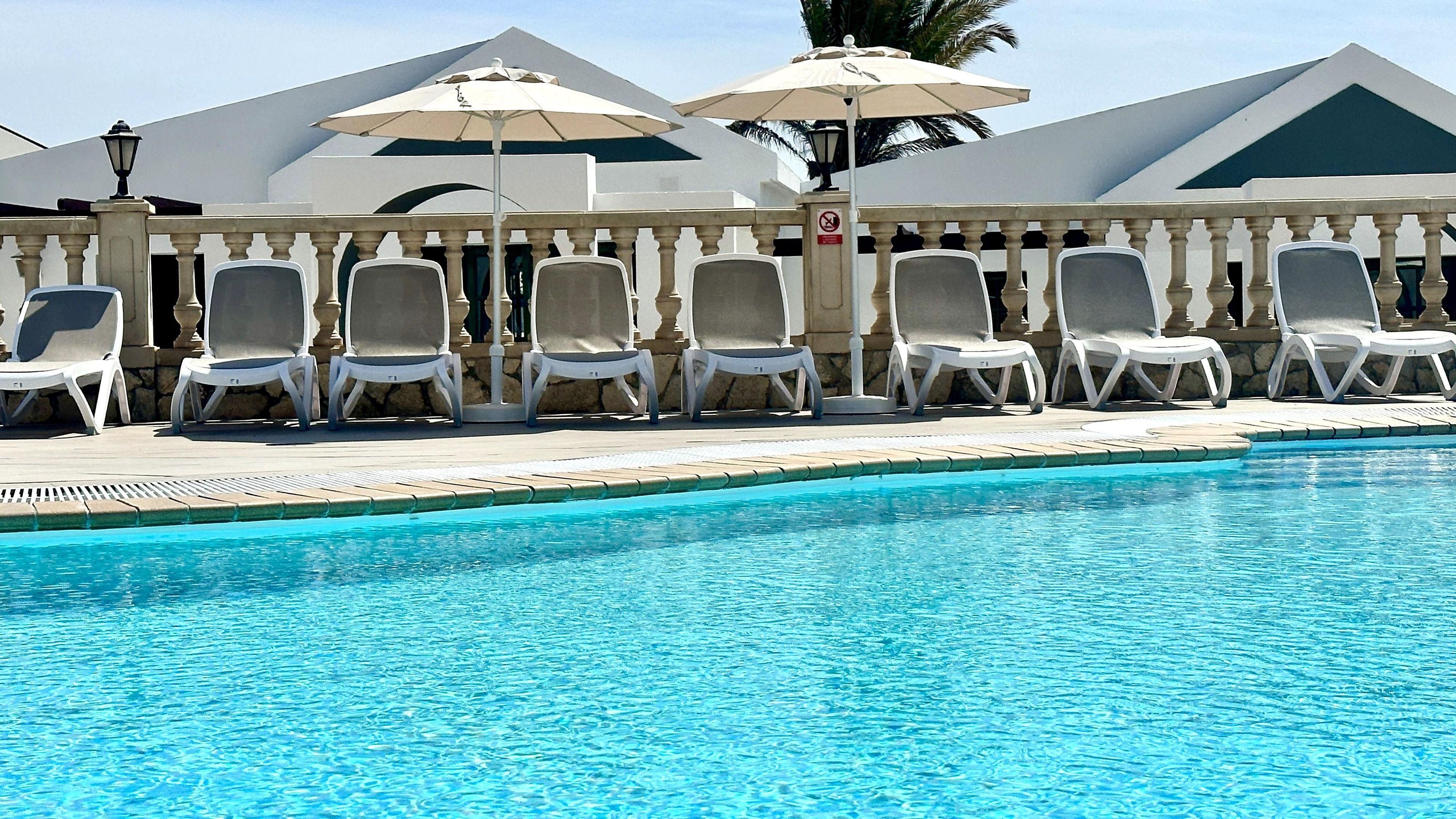 Piscina con sillas de descanso y sombrillas.