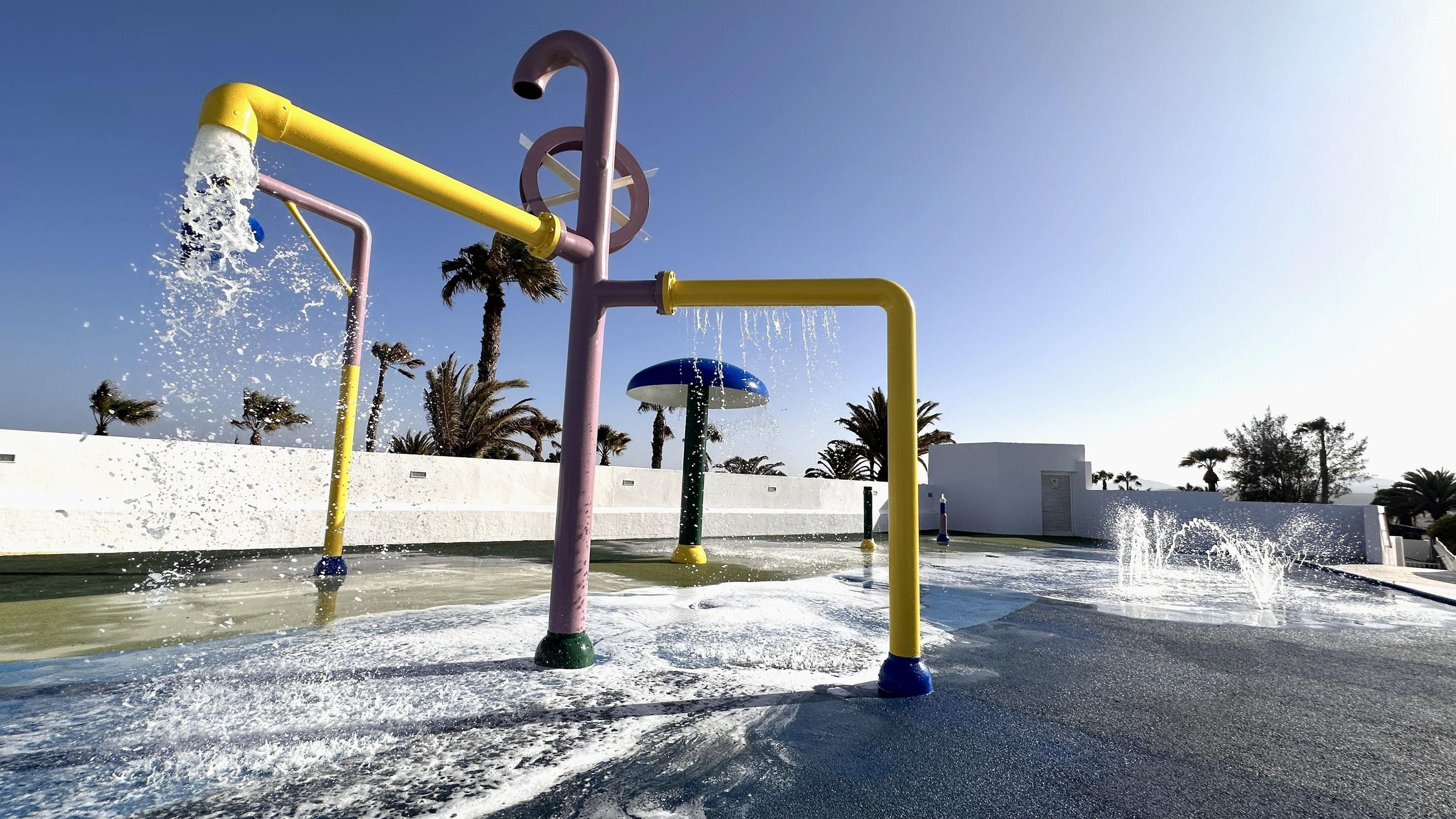 A water play area with multiple fountains and a clear sky.