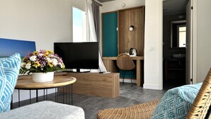 Una sala moderna con televisor de pantalla plana, una planta en maceta y un sillón de mimbre.