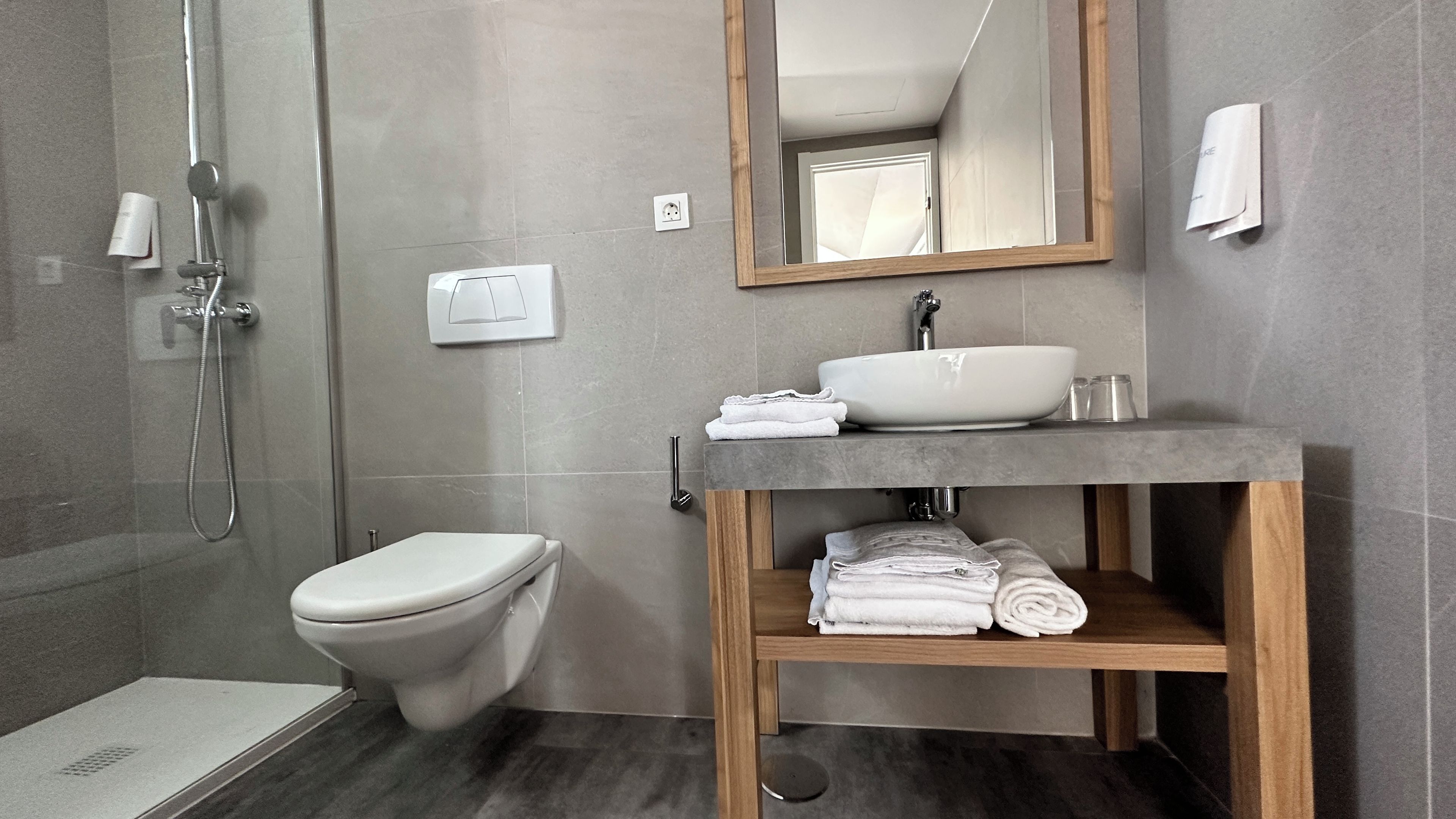 A modern bathroom with a toilet, a sink, and a shower.