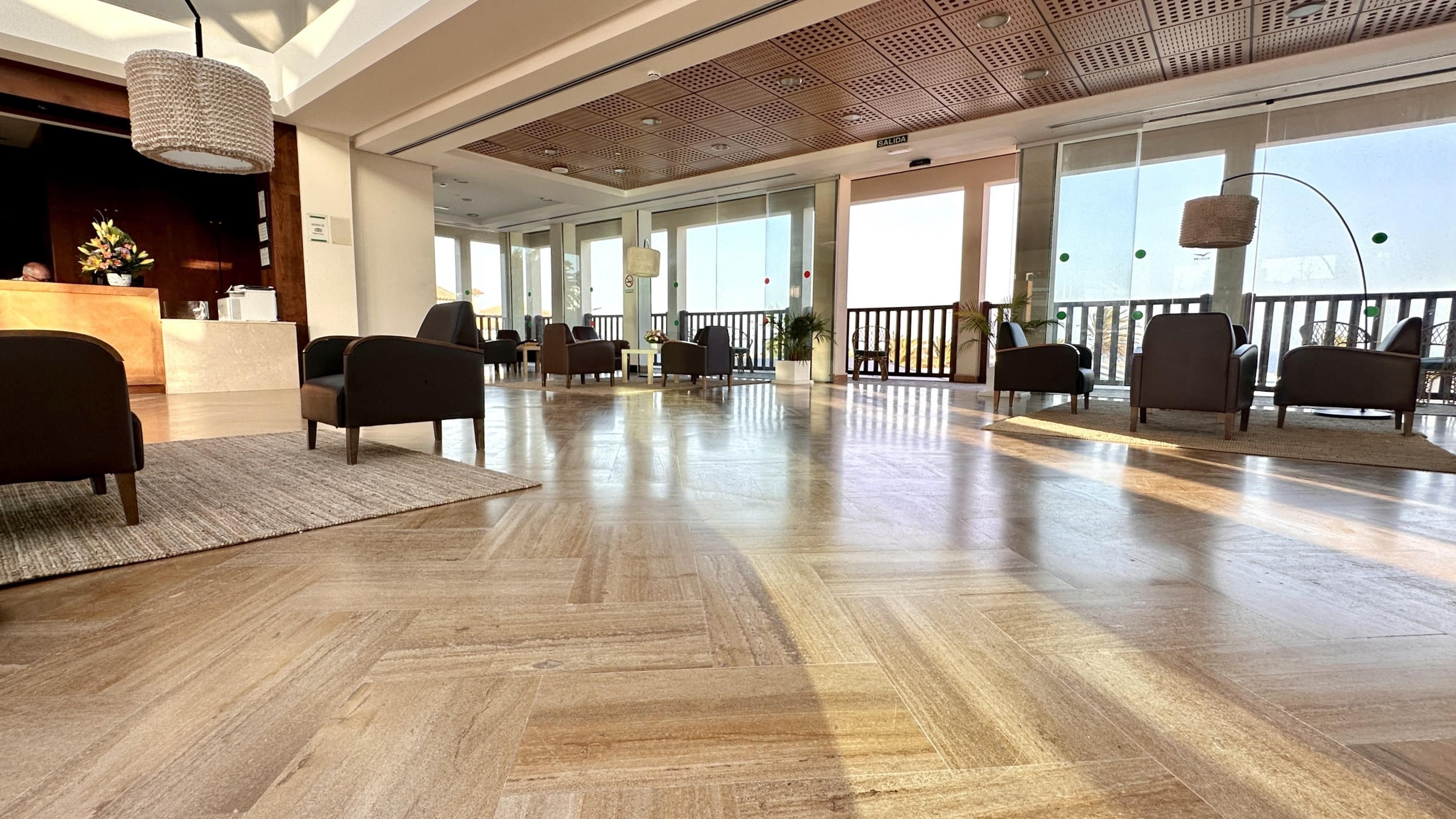 Un vestíbulo amplio con piso de madera, muebles modernos y ventanas grandes.