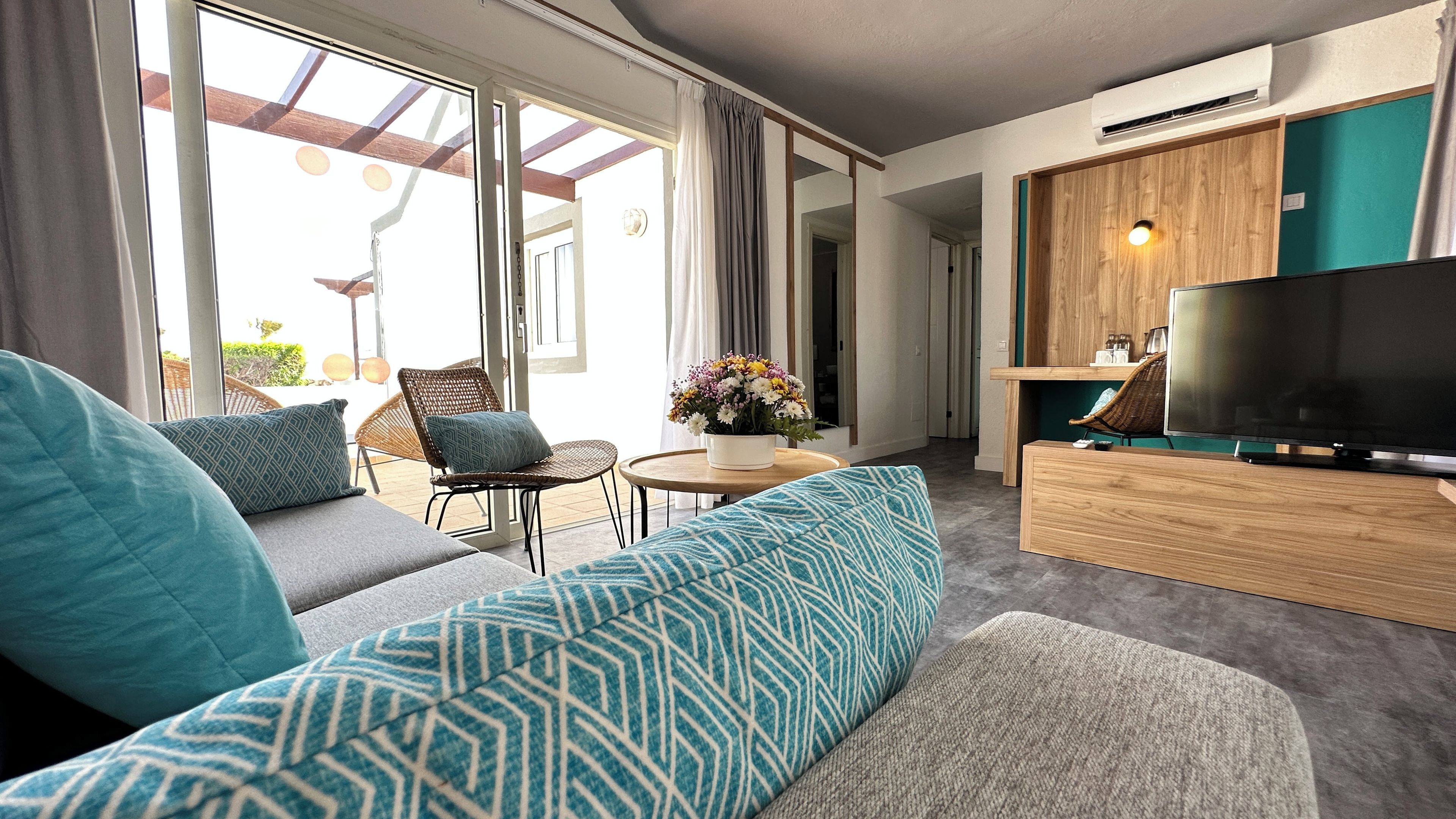 Una sala de estar moderna con un sofá, un televisor y un comedor con mesa y sillas.