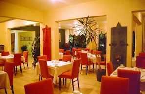 A restaurant with tables set for dining, chairs, and a large plant in the center. - Pinar Hotel (Alanya)