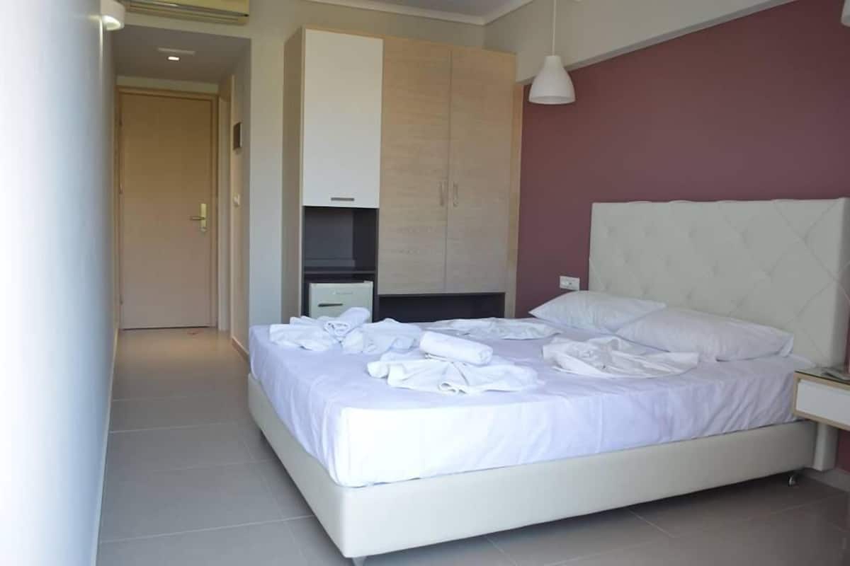Une chambre d’hôtel moderne équipée d’un grand lit, d’une armoire, d’un bureau et d’une télévision.