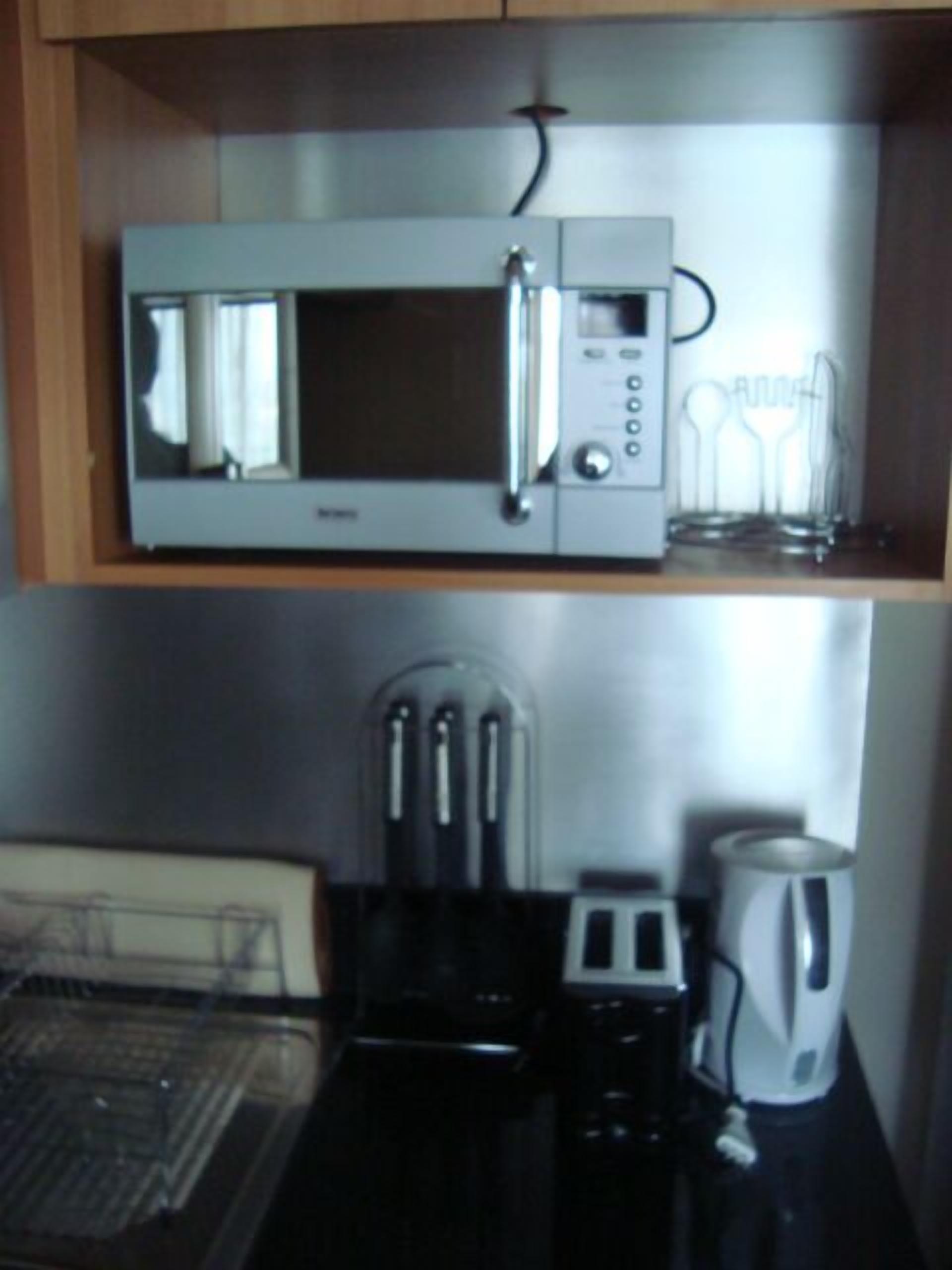 Una cocina compacta con microondas, tostadora y cafetera.