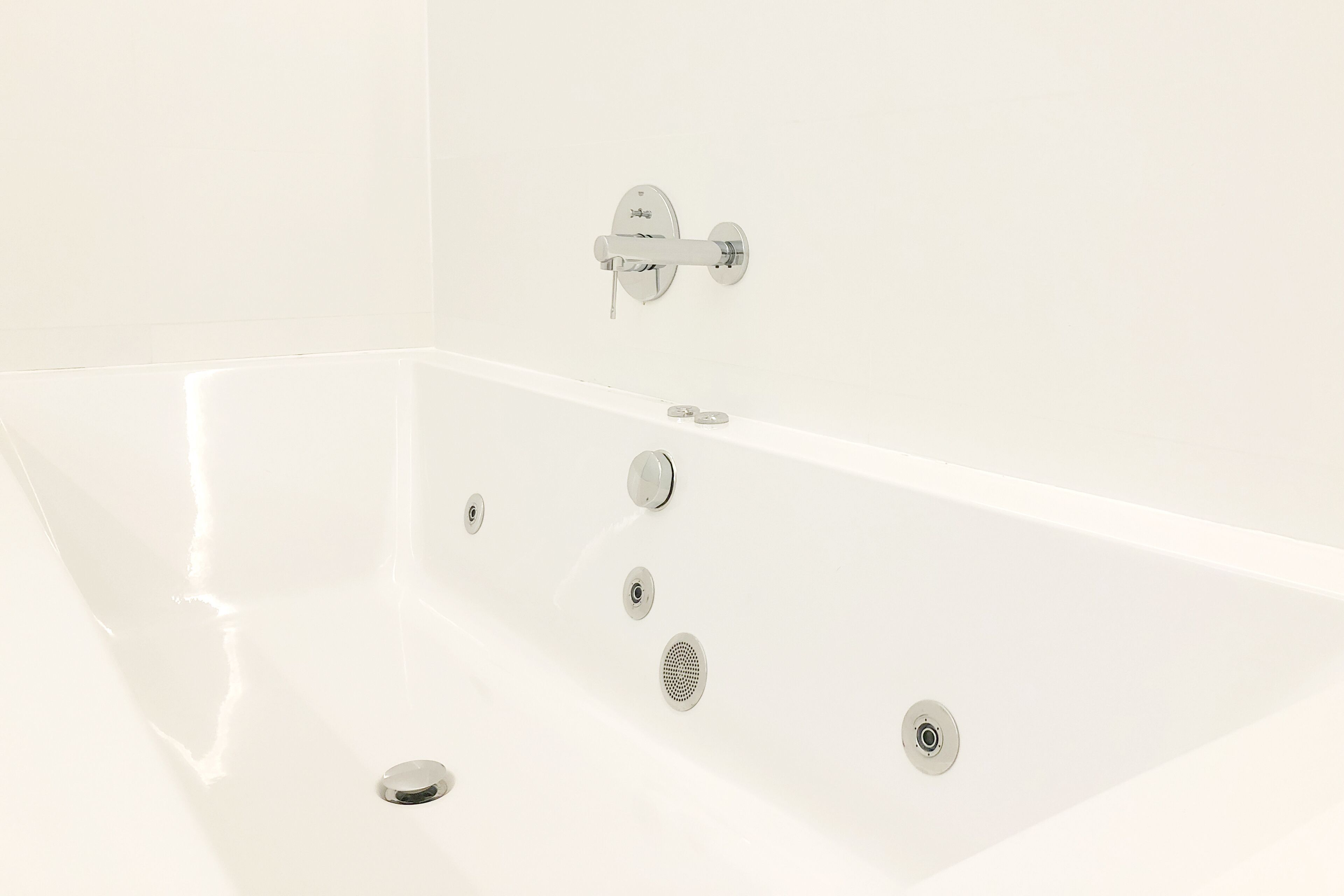 A white bathtub with a modern faucet and a single drain.