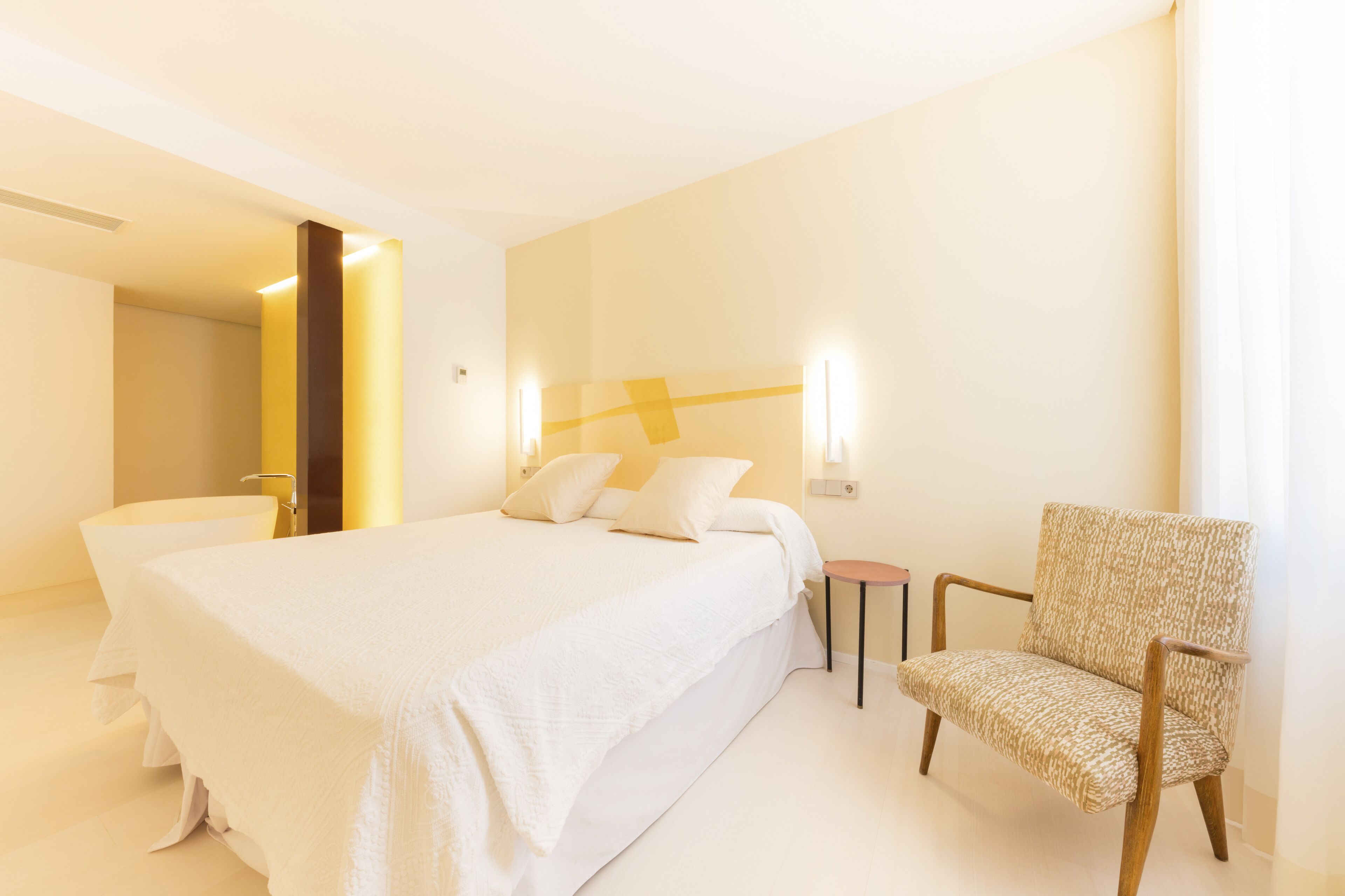 A hotel room with a large bed, a chair, and a small table.