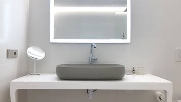Un baño moderno con un tocador blanco, un espejo redondo y un espejo rectangular sobre el lavabo.
