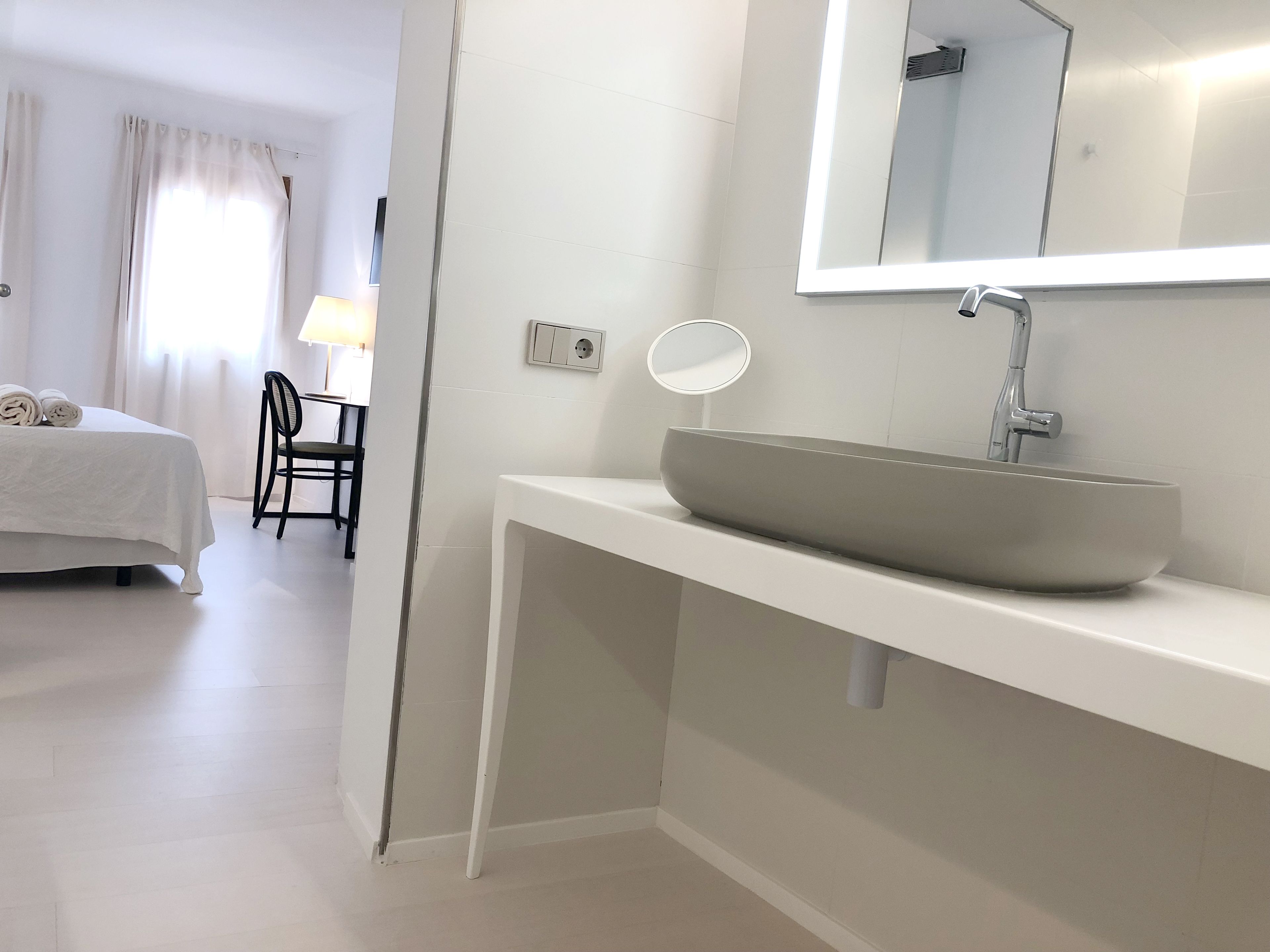 A modern bathroom with a large vessel sink, a mirror, and a power outlet on the wall.