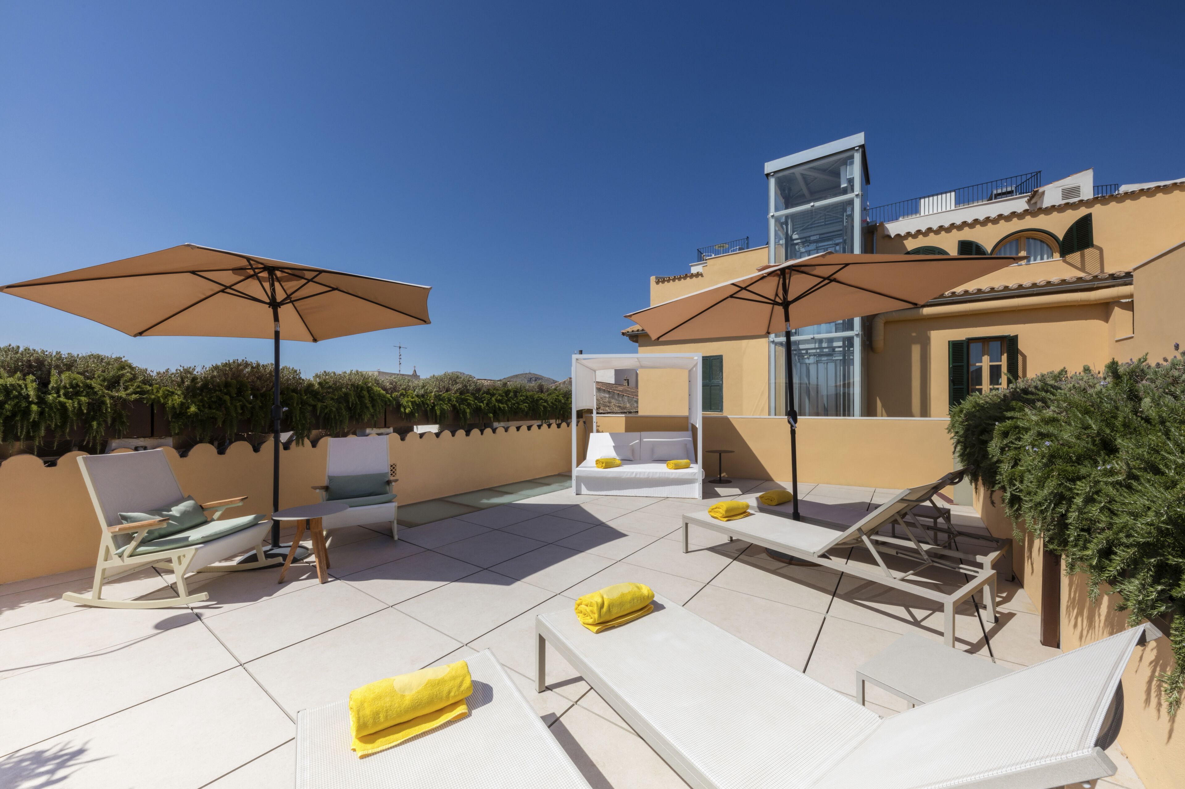 Terraza en la azotea con sillones, sombrillas y un espacio para sentarse.