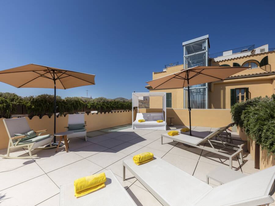 Terraza en la azotea con sillones, sombrillas y un espacio para sentarse.