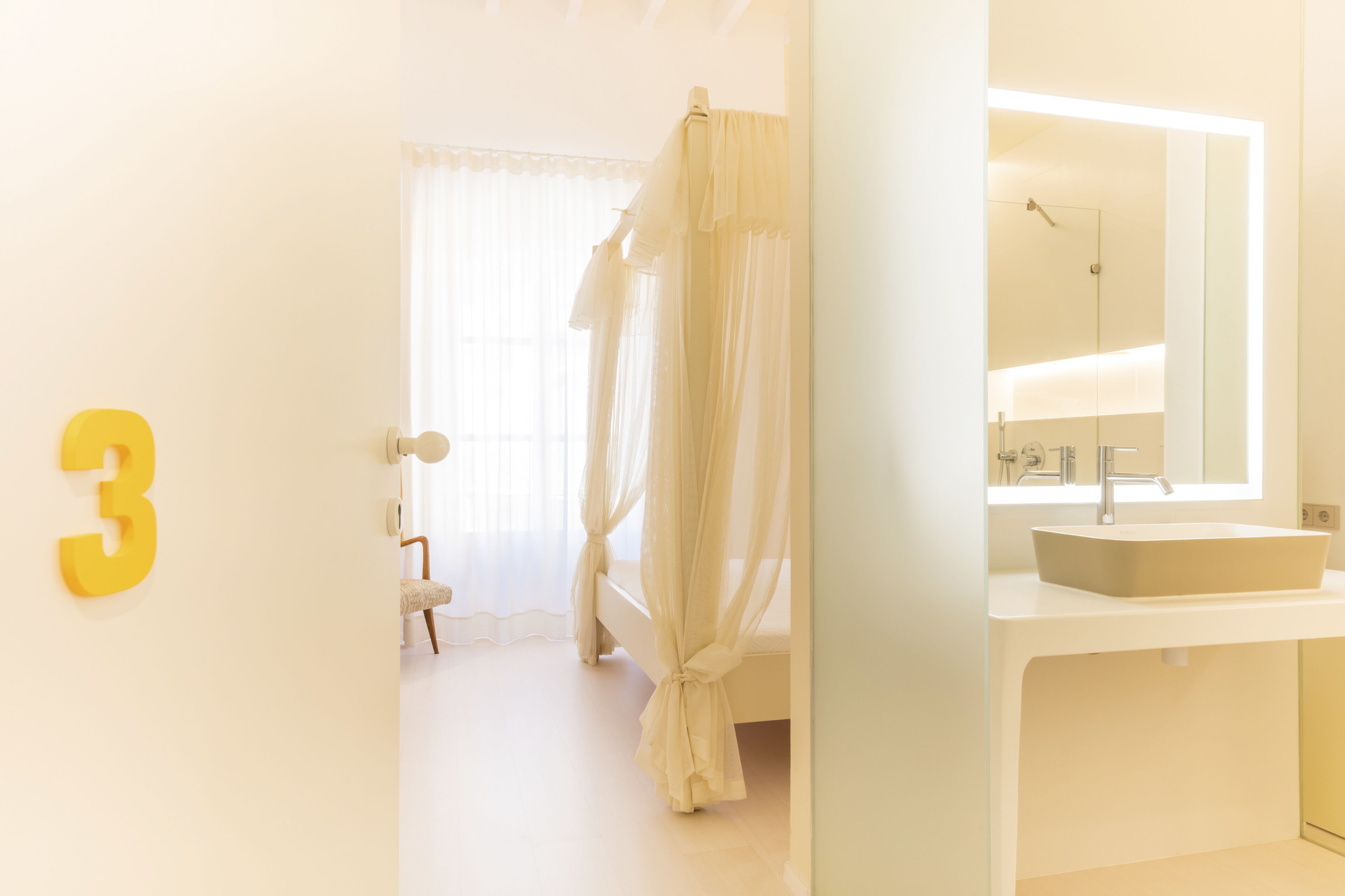 Une chambre à coucher avec un lit, une salle de bain avec un lavabo et un miroir, et une porte portant le numéro 3.