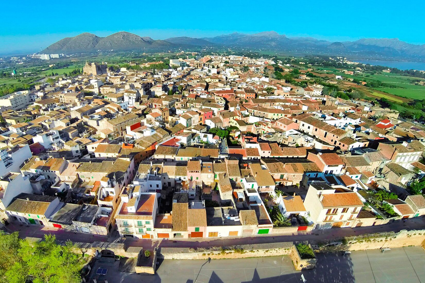 An aerial view of a densely packed town with historic buildings, a prominent church, and a river in the foreground.