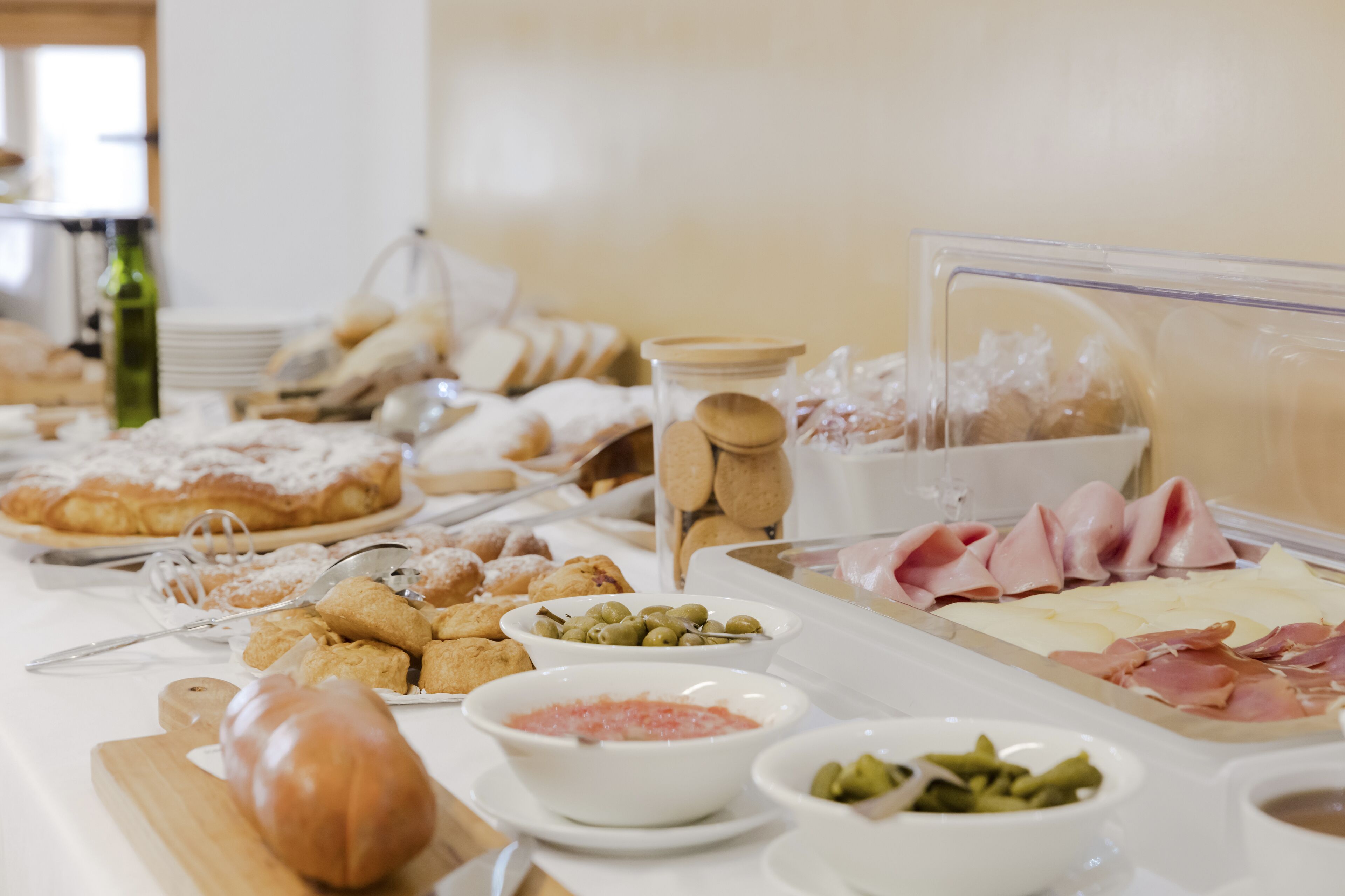 A buffet with various food items including pastries, meats, and olives.