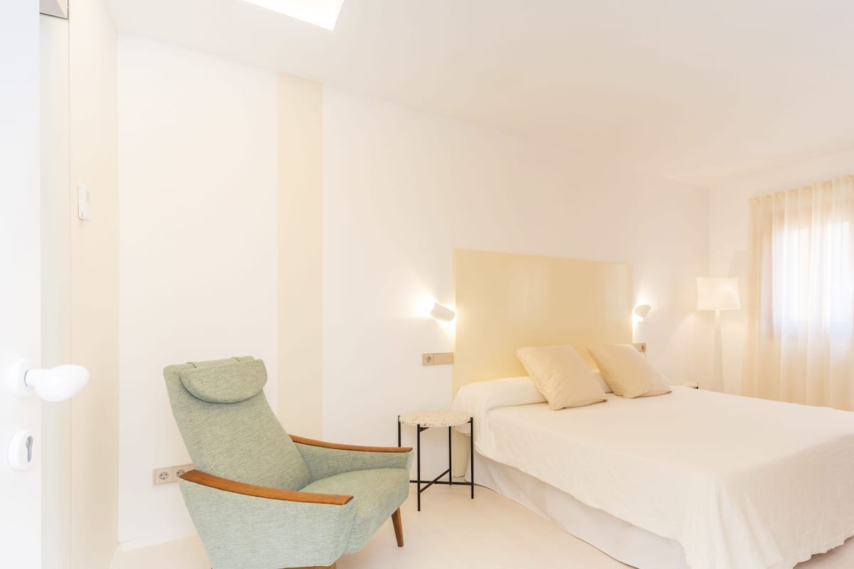 A bedroom with a bed, a chair, and a nightstand.