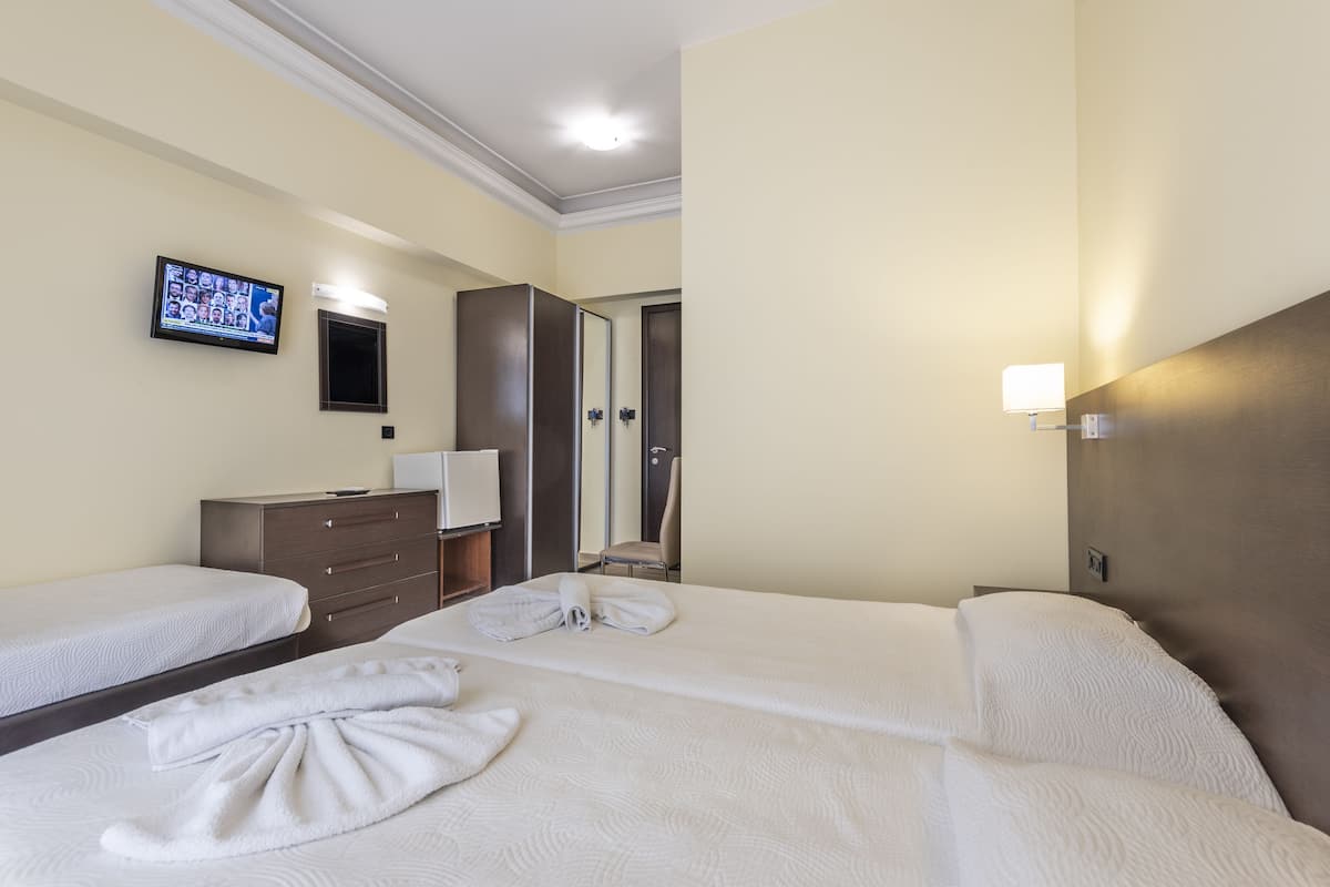 A hotel room with two beds, a TV, a dresser, and a mirror.