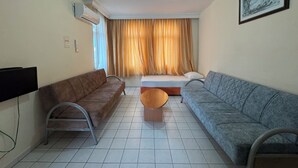 Un salon avec deux canapés, une table basse, un téléviseur et un lit doté de rideaux.