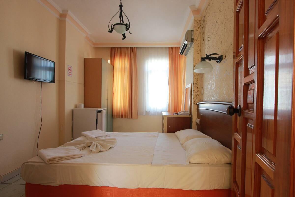 Una habitación de hotel con cama, televisión, escritorio y armario.
