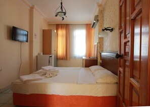 Een hotelkamer met een bed, een televisie, een bureau, een spiegel en een kledingkast.