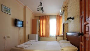 Une chambre d’hôtel équipée d’un lit, d’une télévision, d ’un climatiseur, d’un téléphone et d’une fenêtre avec des rideaux.