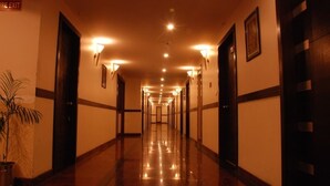 A long, well-lit hallway with doors on both sides, leading to rooms. - Hotel Softel Plaza (Dehradun)